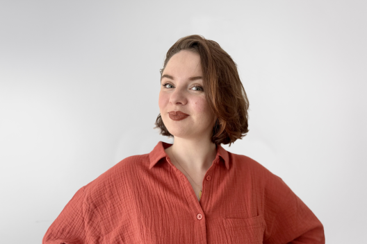 Bethan smiling at the camera. She's a white woman with short brown, wearing a red shirt.