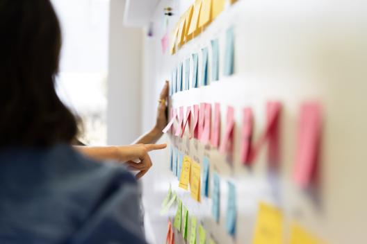 Innovation Unit staff pointing at post it notes on a wall