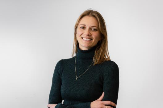 Rachel smiling at the camera. She's a white woman with shoulder length hair, wearing a black turtle neck