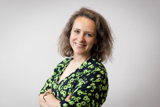 Sarah smiling at the camera. She's a white woman with brown hair, wearing a green and black dress