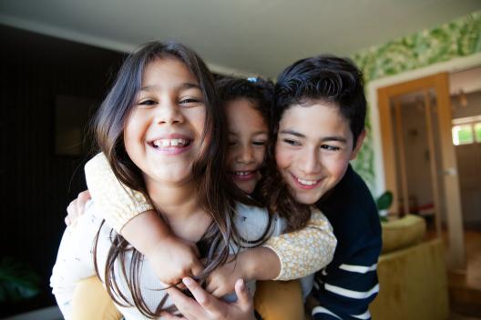 Three children smiling and hugging each other