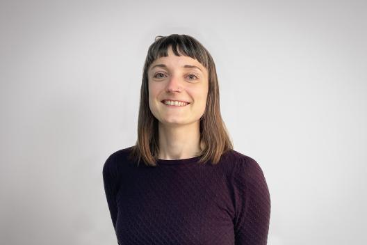 Anne smiling at the camera. She's a white woman with a fringe, wearing a purple jumper