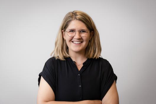 Ellen smiling at the camera. She's a white woman with short blonde hair, wearing a black shirt and glasses.