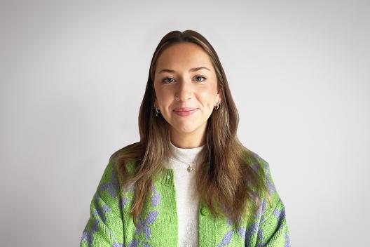 Fran smiling at the camera. She's a white woman with dark blonde hair, wearing a green cardigan