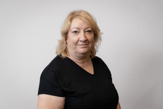 Julie smiling at the camera. She's a white woman with shoulder length blonde hair, wearing a black top