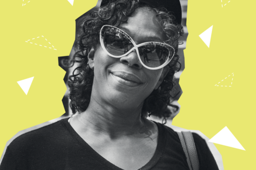 A Black woman wearing sunglasses smiles at the camera