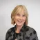 Frances smiling at the camera. She's a white woman with short blonde hair, wearing a grey and black jacket