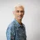 Aviv smiling at the camera. He's a man of colour with short grey hair, wearing a blue Hawaiian shirt