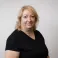 Julie smiling at the camera. She's a white woman with shoulder length blonde hair, wearing a black top