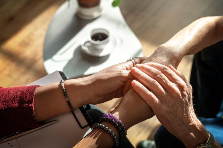 Two people holding hands over a table, supportively
