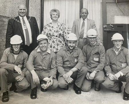 A black and white image of men smiling at the camera, who are part of the workforce in Borough