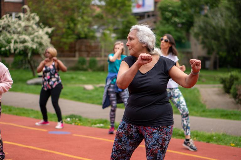 Four women in an exercising class in an outdoor multipurpose public space. 