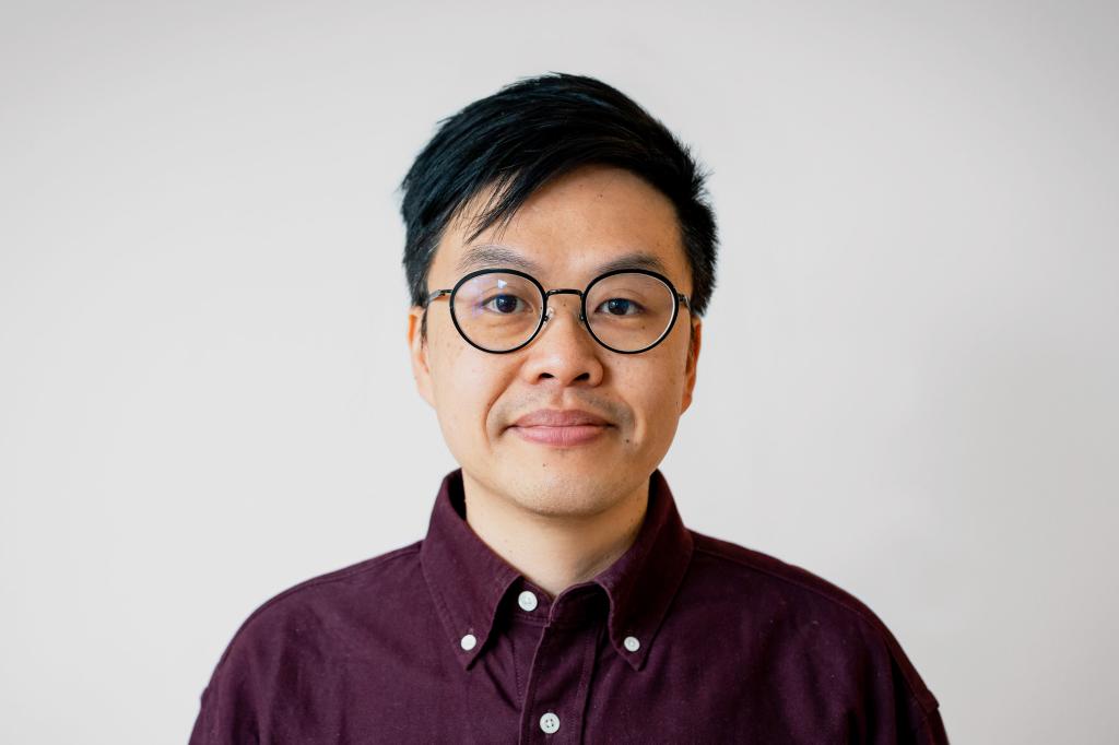 Yin Hei Ho looking at the camera. He is wearing glasses and a burgundy shirt.
