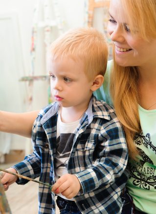 Child painting with encouragement from adult