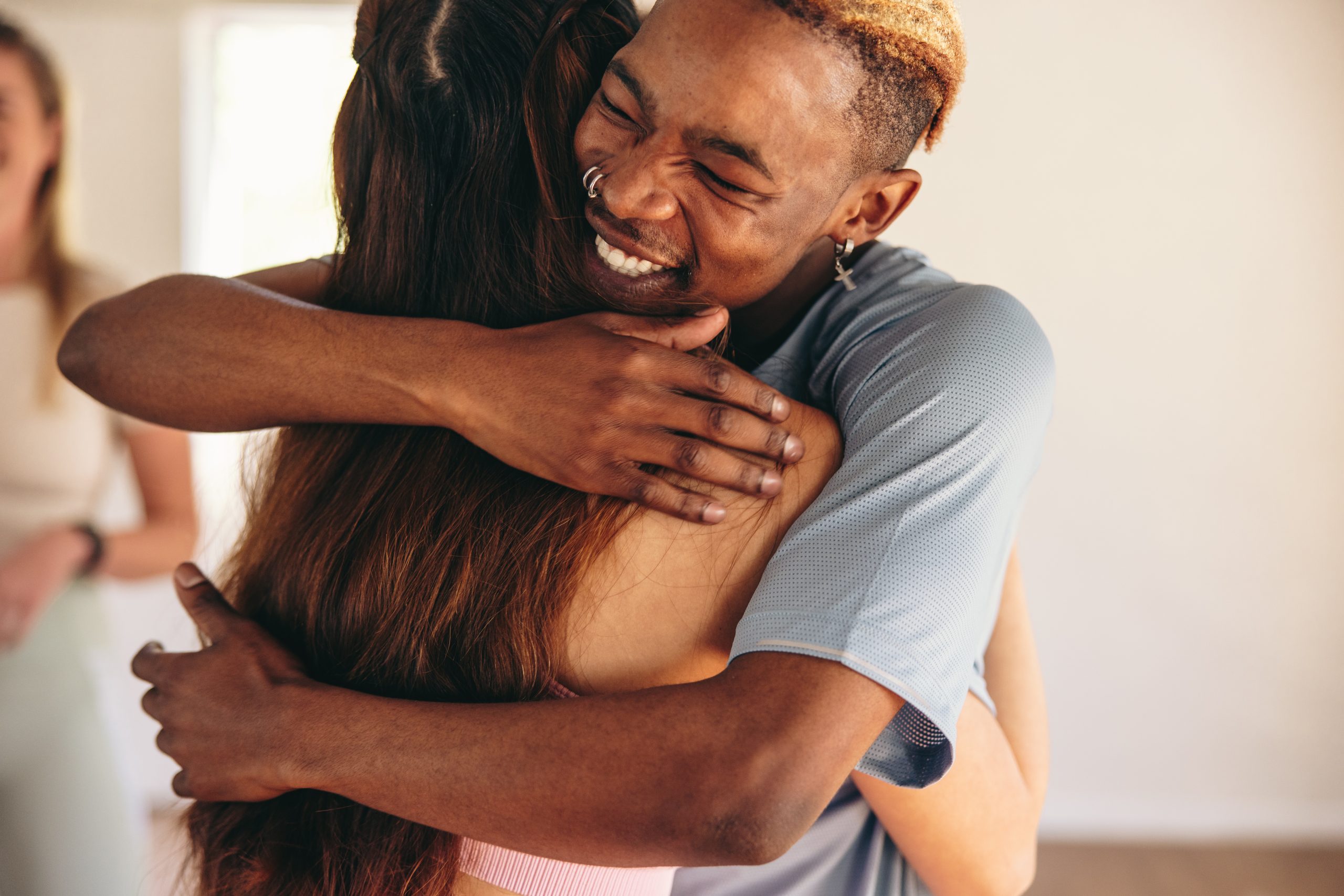 Young man embracing his fitness friend in a yoga studio. Two young people saying goodbye after a yoga session in a community fitness studio.