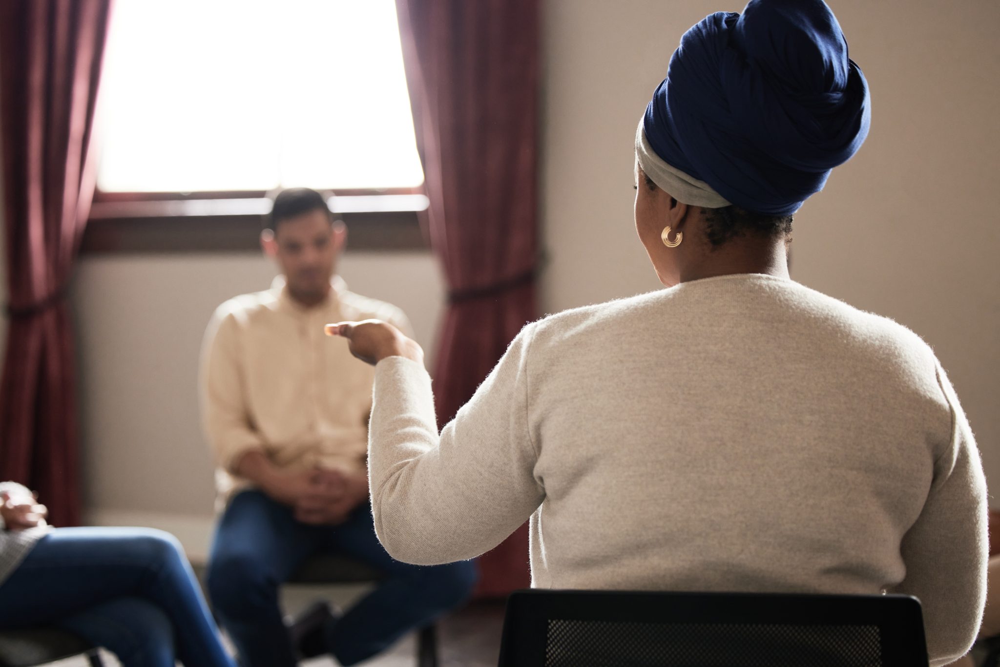 Support, black woman and group of people in therapy with understanding, sharing feelings and talking in session. Mental health, addiction or depression, men and women with therapist sitting together