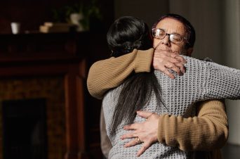 Two women hugging and supporting each other's mental health